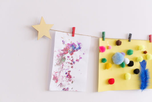 Gold star kids art display mounted on a wall, hanging artwork with colourful wooden clothes pegs