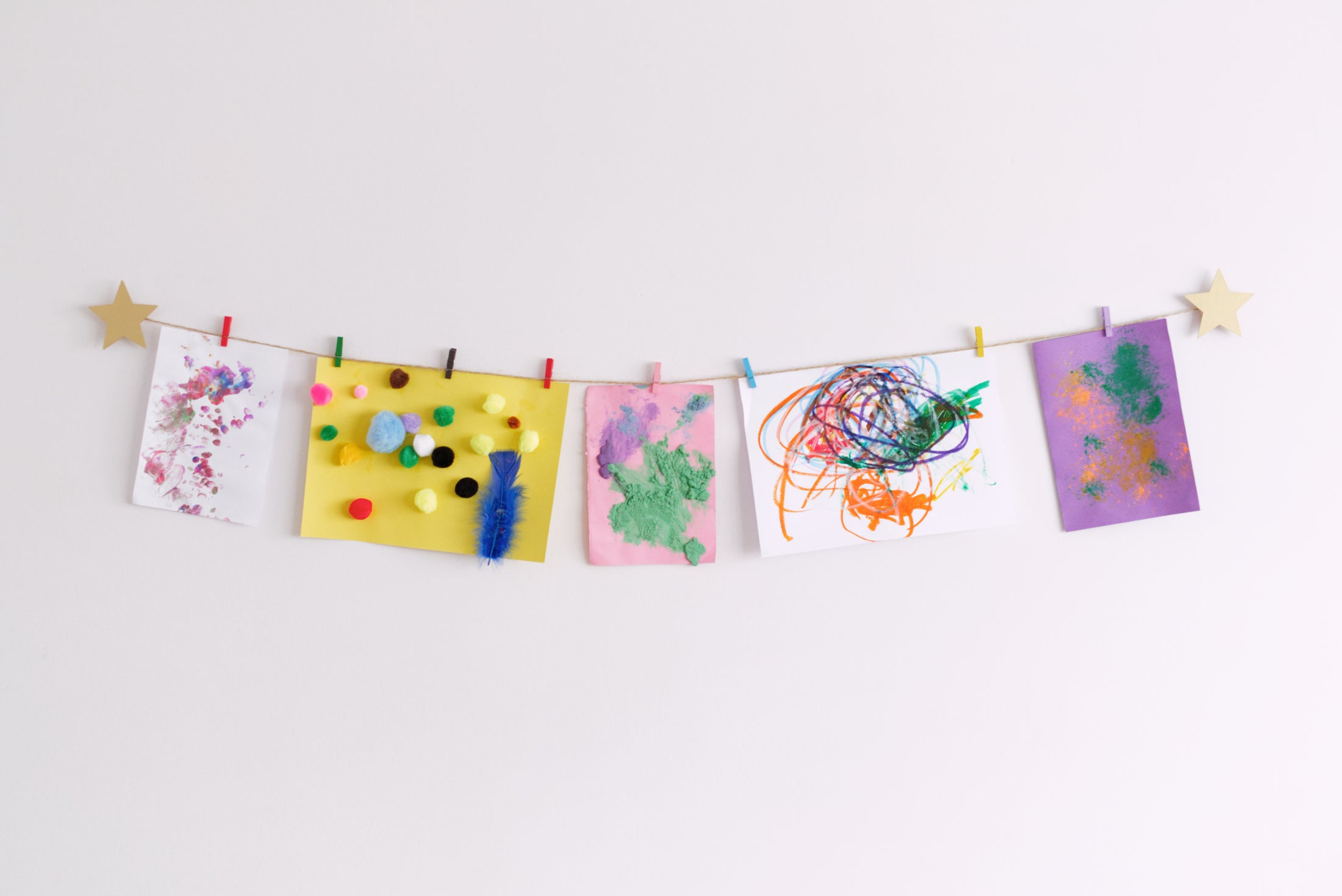 kids art display wall decor with gold stars and colourful mini clothespins hanging artwork