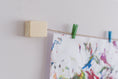 Load image into Gallery viewer, close up of wooden wall mount of kids art display with two mini clothes pegs hanging up a painting
