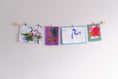 Load image into Gallery viewer, handmade natural wood and twine kids art display mounted on wall showcasing vibrant paintings
