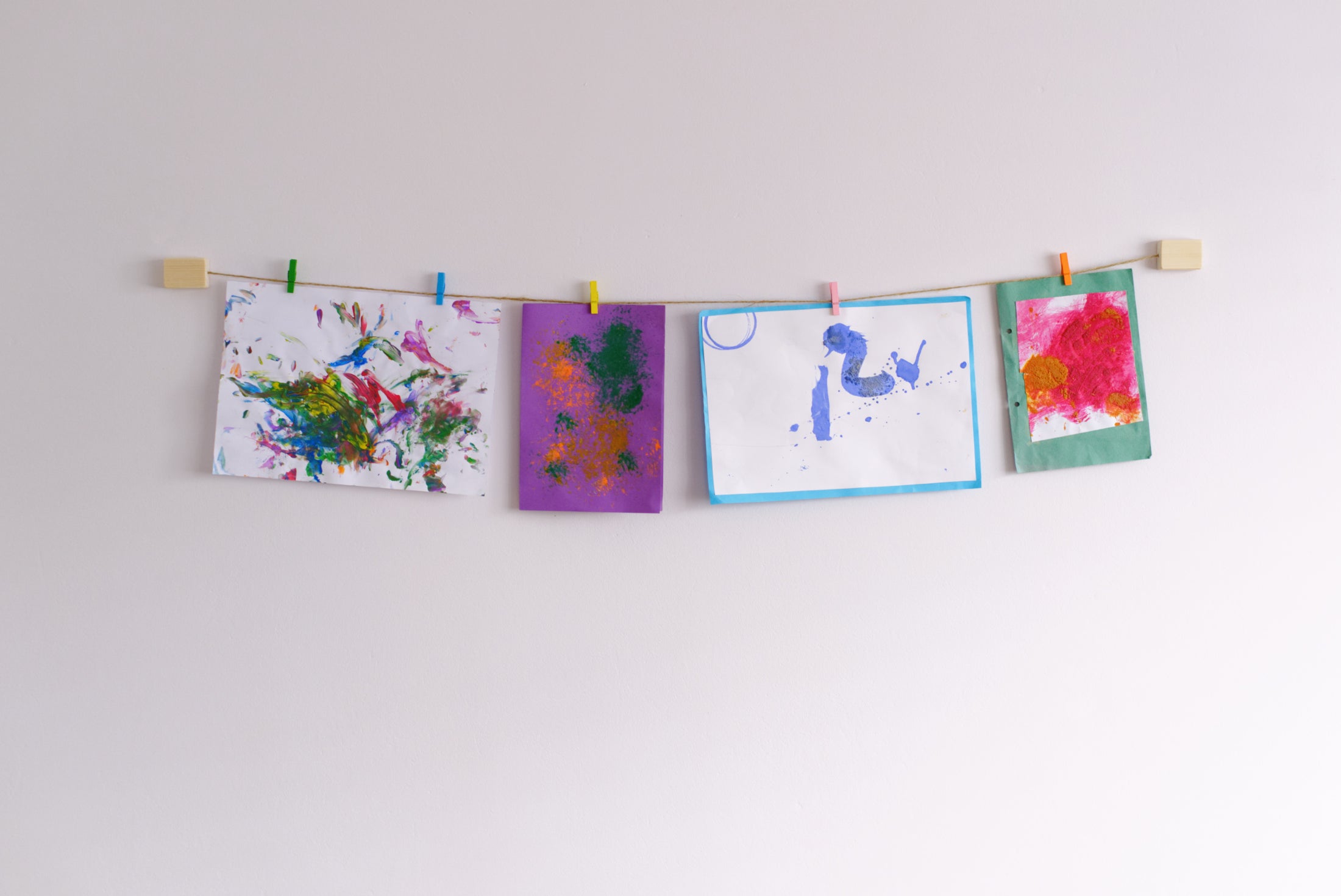 handmade natural wood and twine kids art display mounted on wall showcasing vibrant paintings